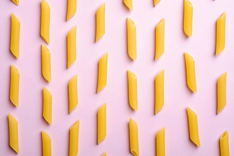 a large amount of yellow pasta sprinkles arranged in a pattern on a pink surface