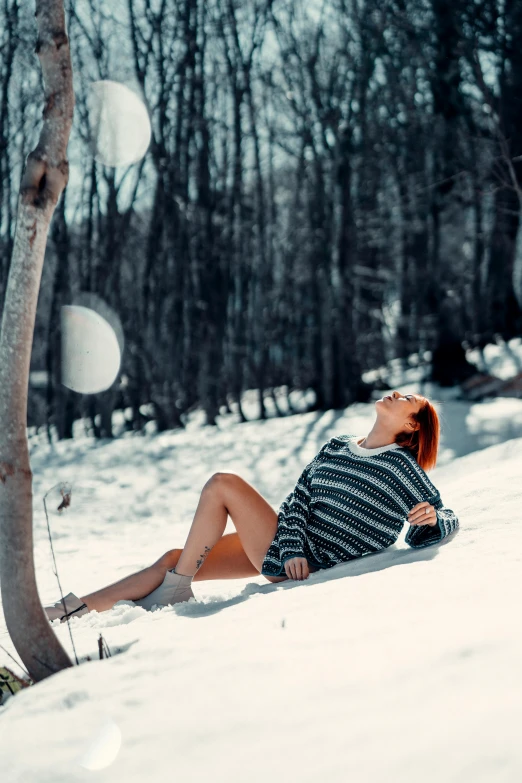 the woman is laying on the snow in a black and white shirt