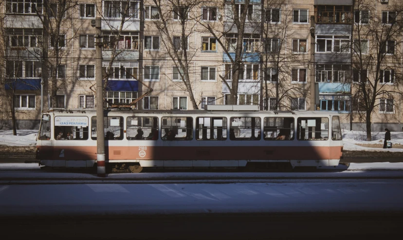 a red and white trolly going by a building