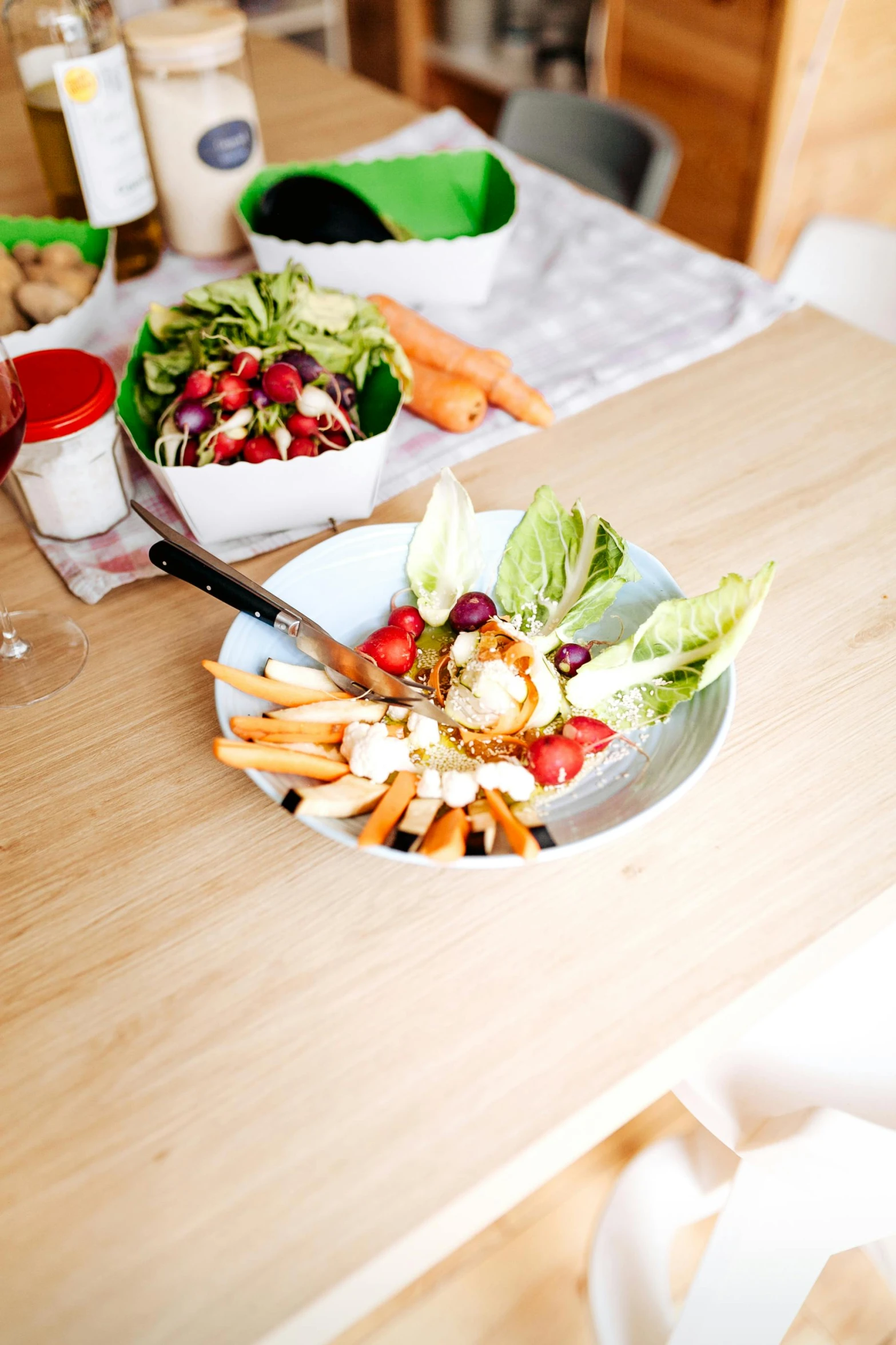 two bowls and a knife sit on a wooden table with food in them