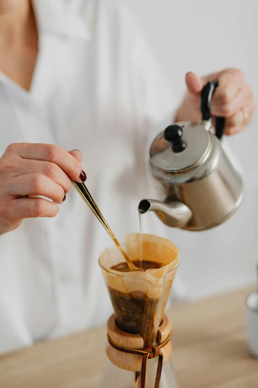 woman pouring coffee into a glass coffee mug