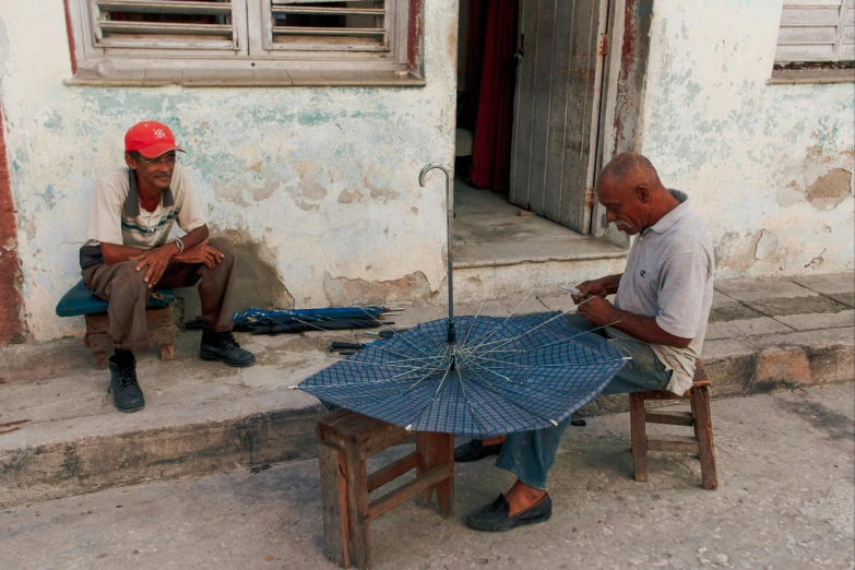 two men sit on the street while knitting and sitting down