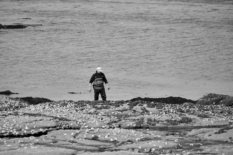 a man standing in the water next to some rocks