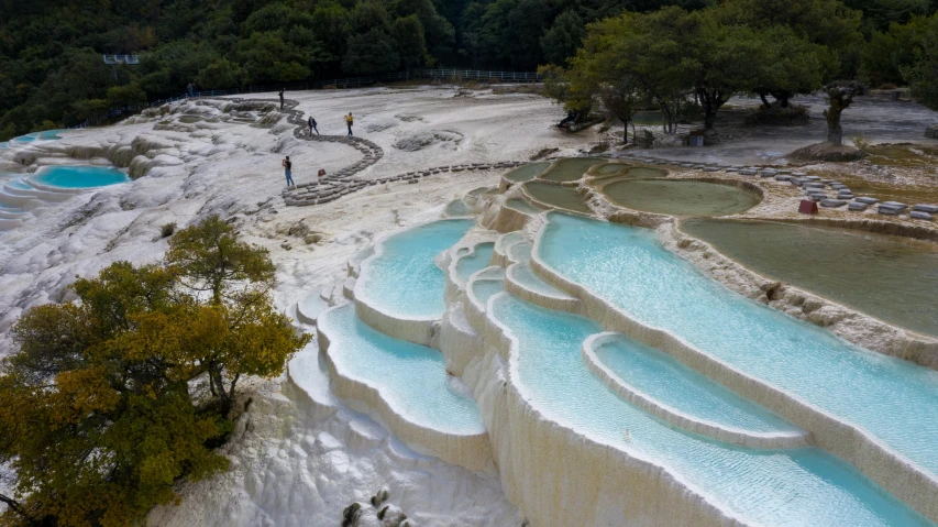 a view of several blue pools next to trees