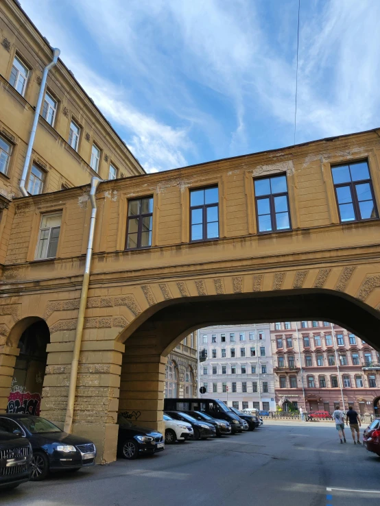 several cars are parked outside an arched yellow building