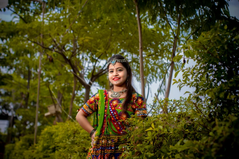 a woman in ethnic dress standing behind trees