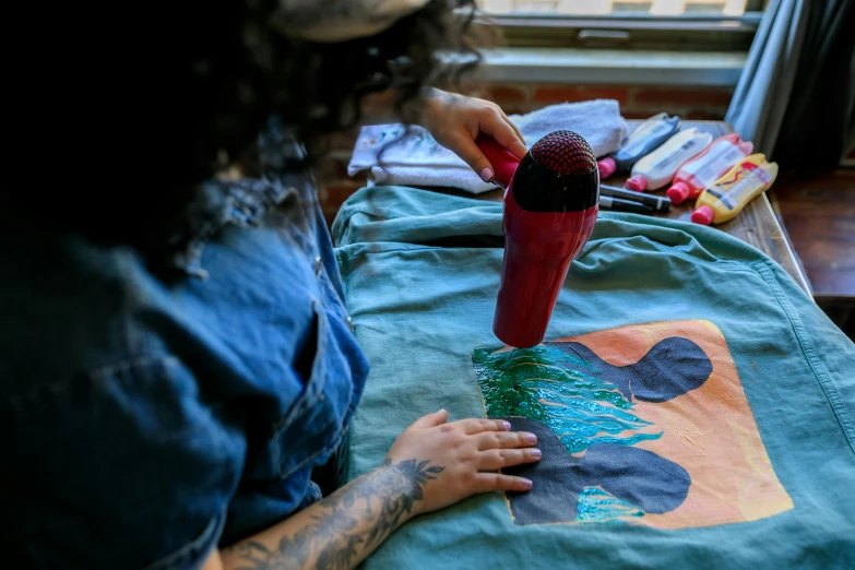 a woman with a tattoo working on a piece of fabric