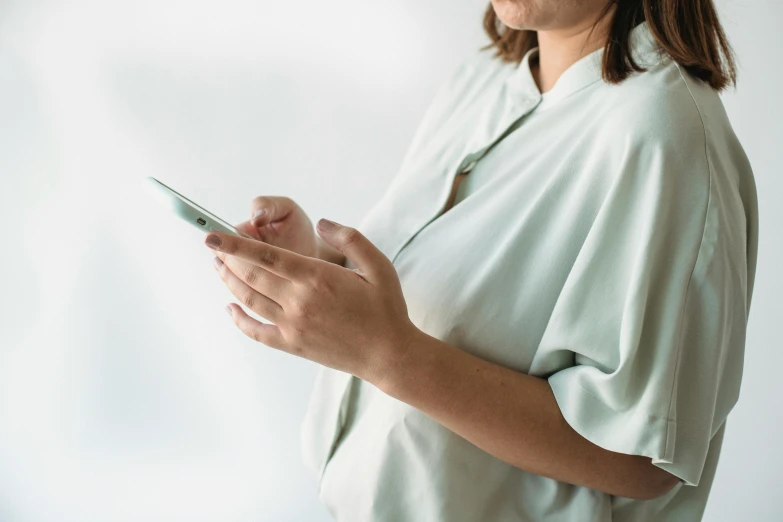 a woman using her cell phone while wearing a white shirt