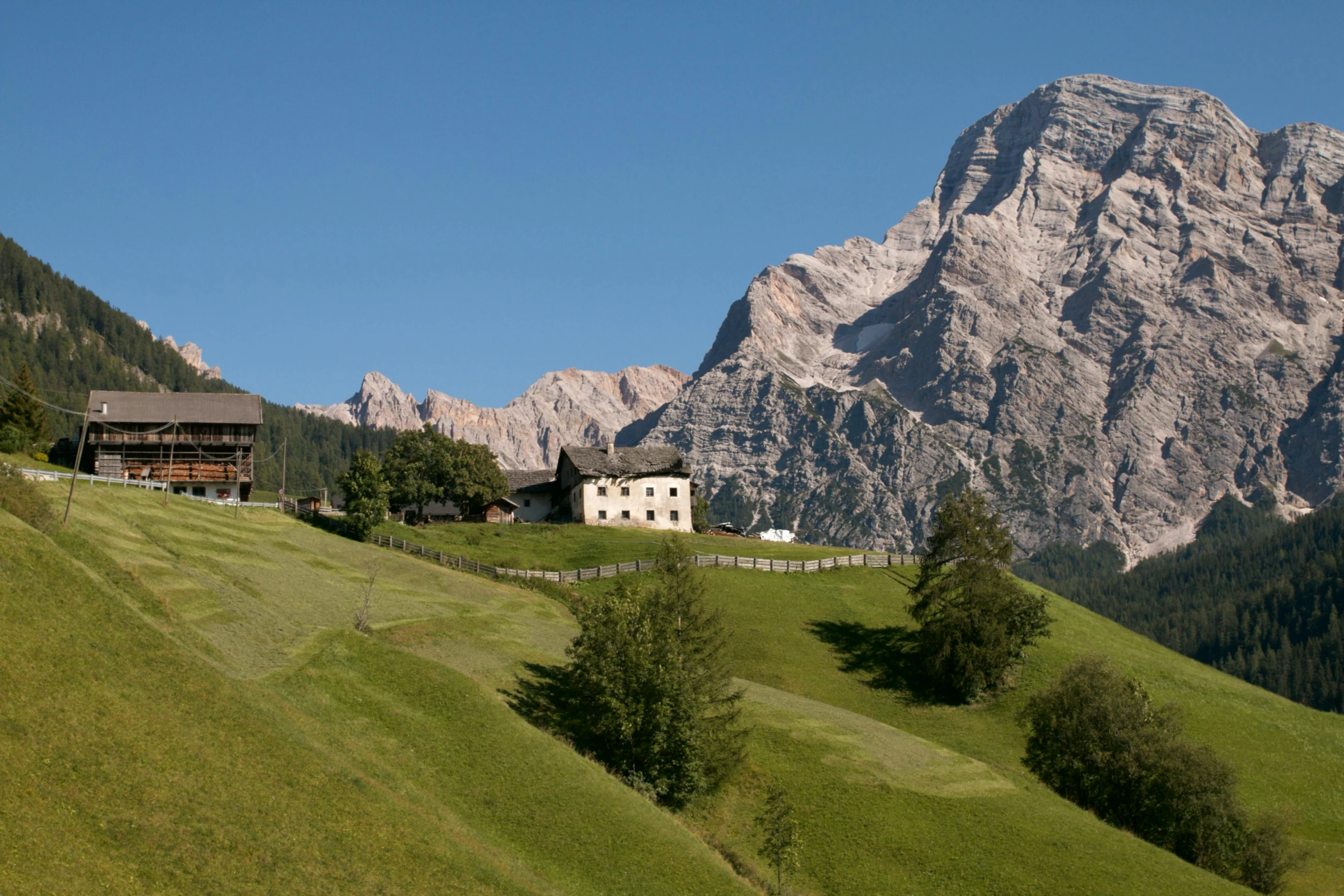 a home on a green hillside with mountains in the background