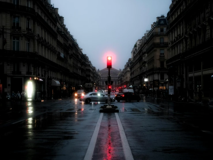 a busy city street with parked cars at night