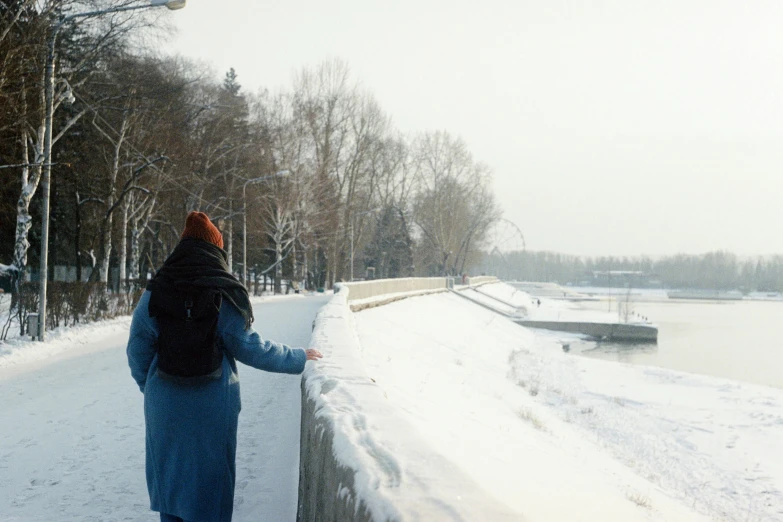 a woman in the snow next to a snow - covered path