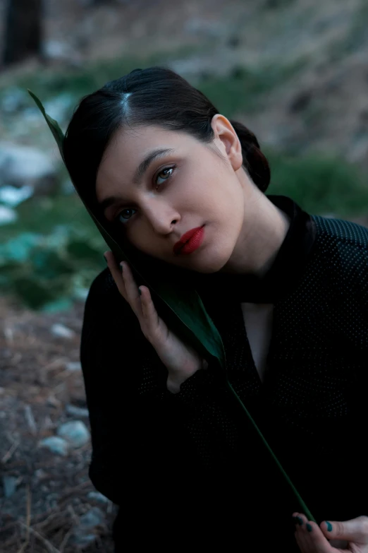 a woman holding a plant with one hand and posing for the camera