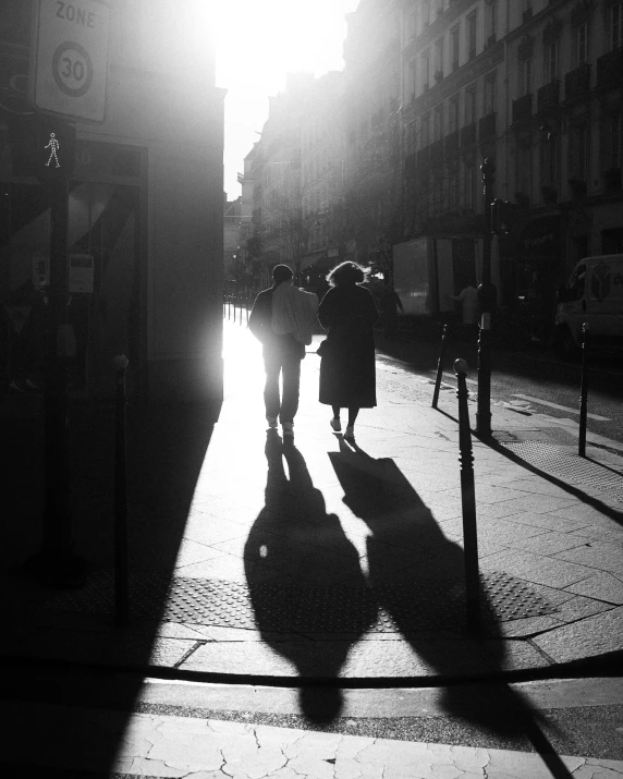 two people standing outside of buildings under the sun