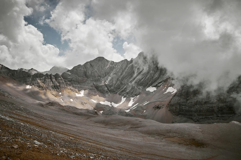 a mountain range with snow and clouds coming in from the top