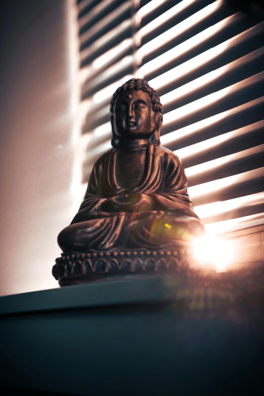 a buddha statue sitting in the middle of a room next to a window