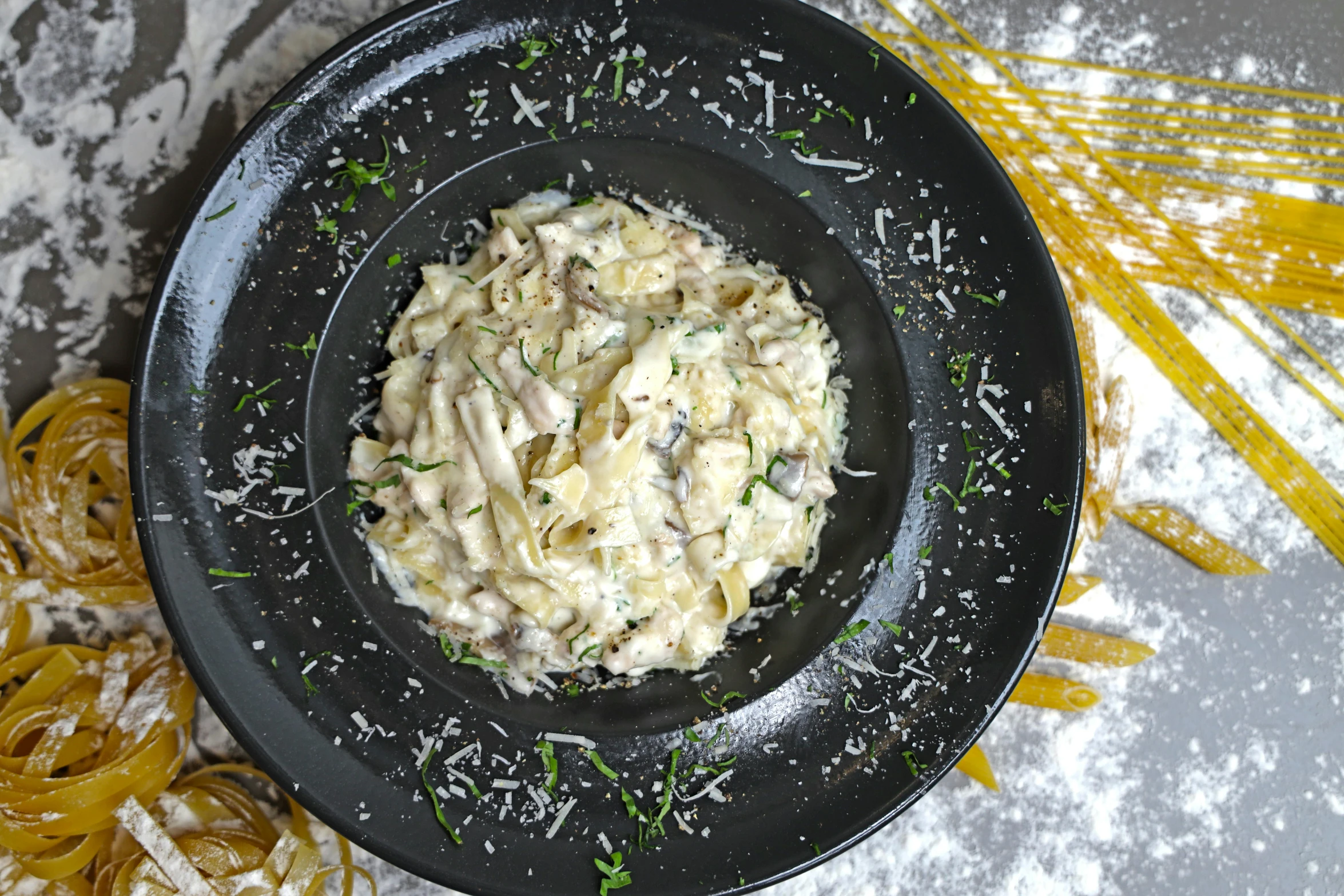 there is pasta in a black plate on a table