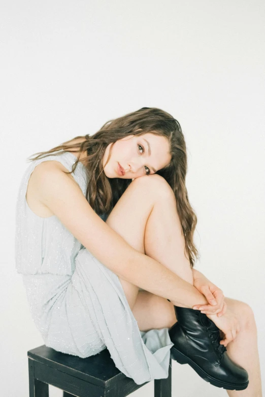 woman posing  on small stool in white room