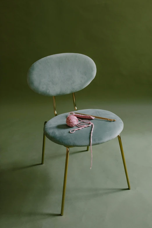 an upholstered, blue chair with a knit ball on it