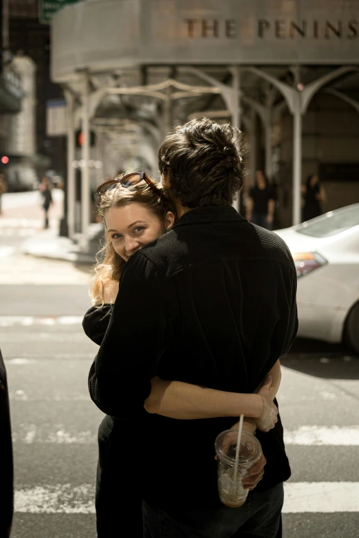 a man and woman hug each other as they walk across the street