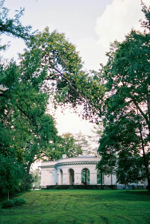 a white building sitting in the middle of a green forest