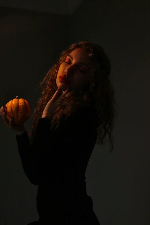 a woman holding a piece of fruit up to her face