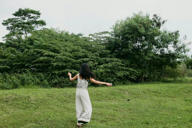 a girl standing in the grass throwing a frisbee