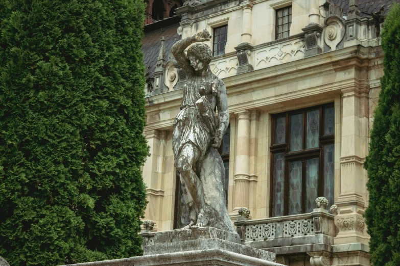 an old stone sculpture sitting in front of a large building