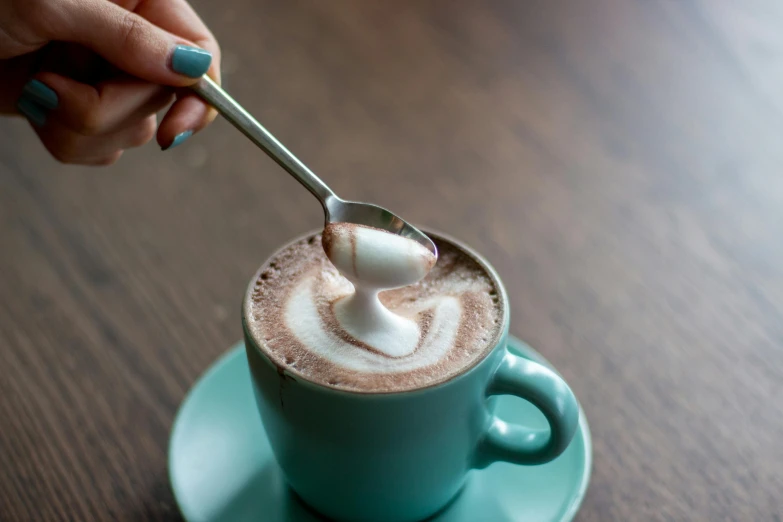 a woman spooning sugar into a  beverage