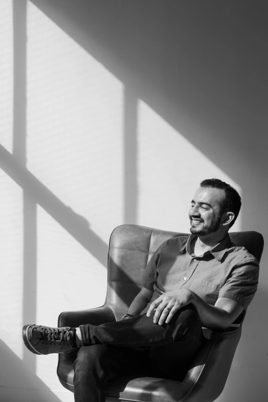 a man sitting in a chair in a room with sun coming through the window