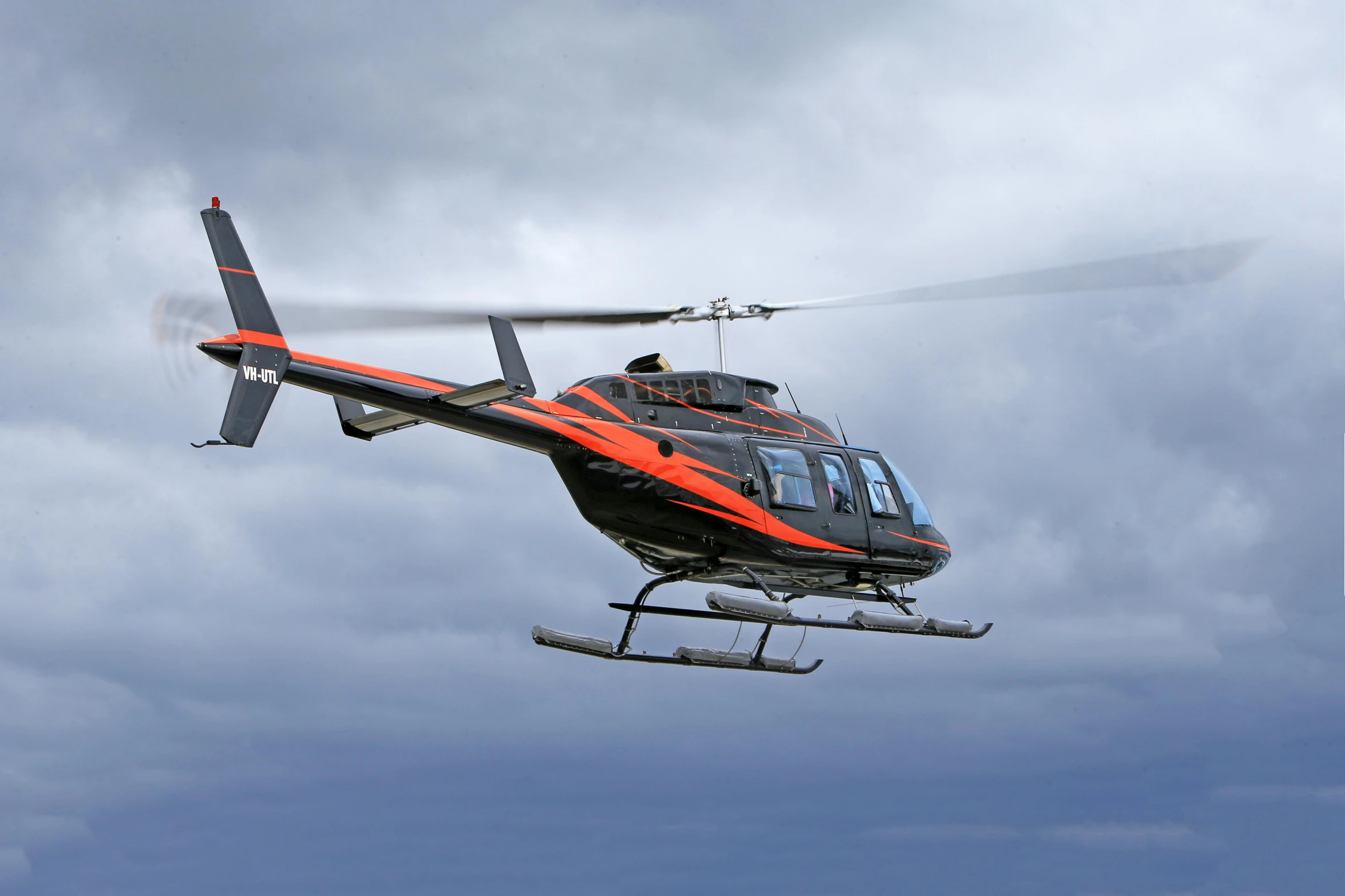 a red helicopter flies in a cloudy sky