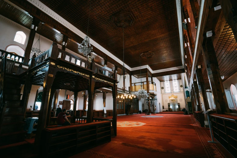 a large room with a long row of wooden pillars and ceilings