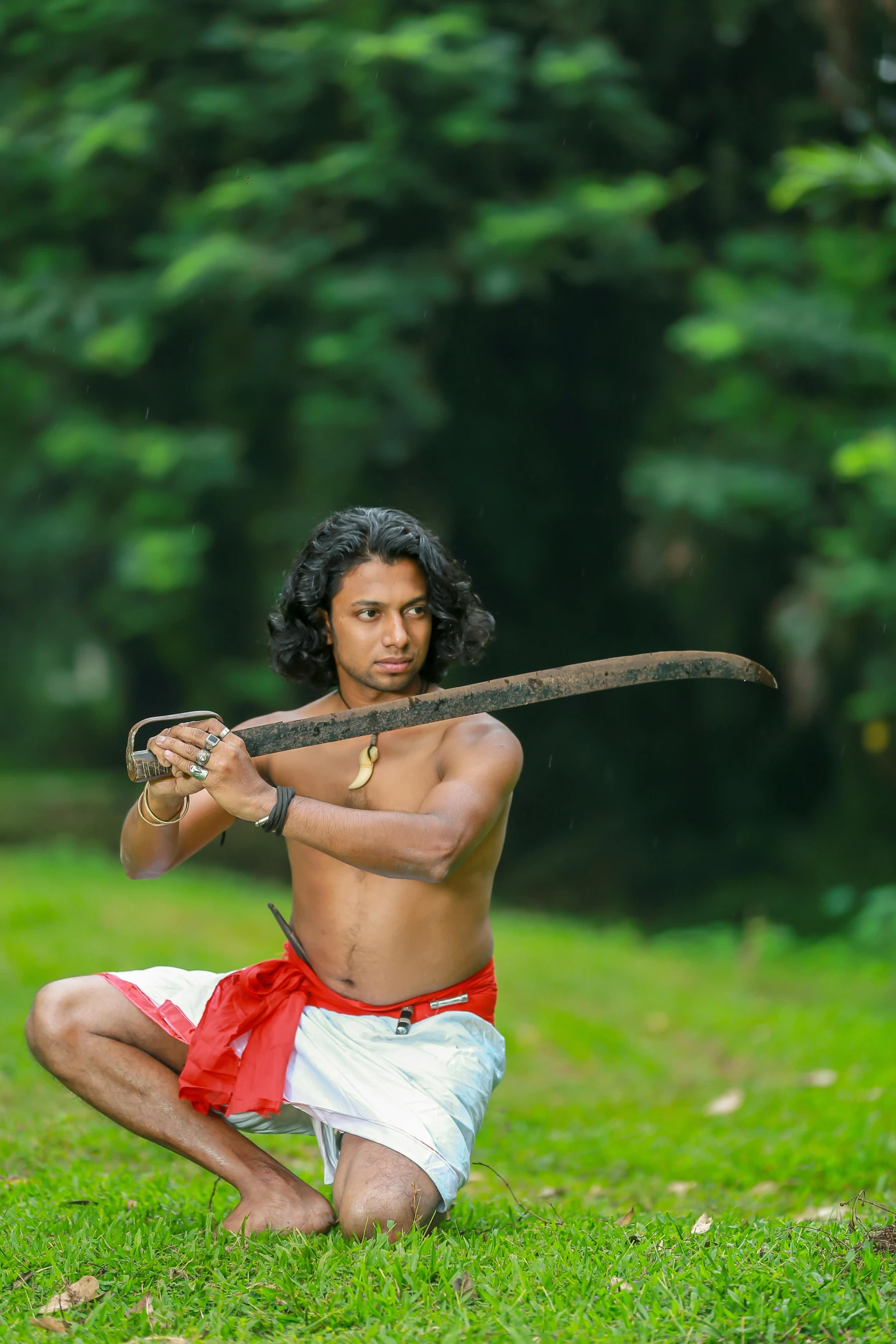 a man with long hair and  is kneeling holding two arrows