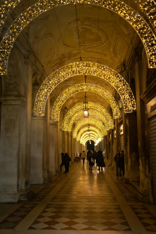 several people walk through a hallway decorated with lights