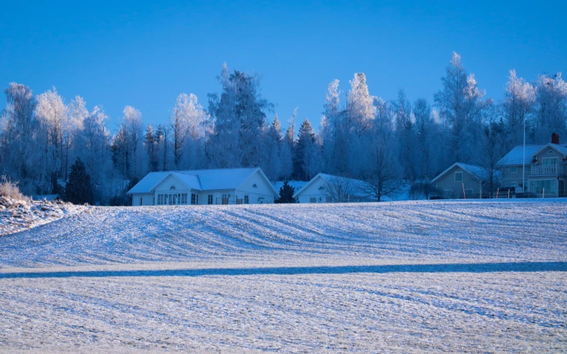 a snow covered field with houses in the background