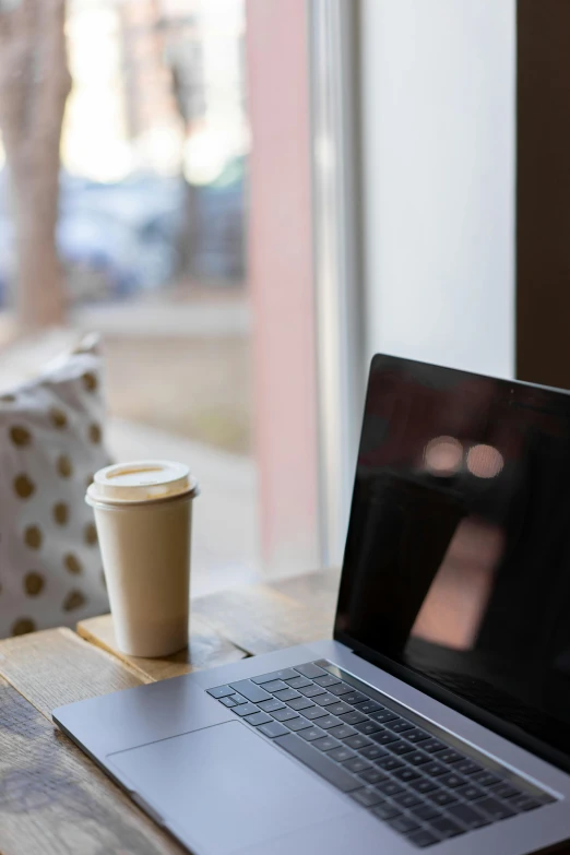 an open laptop with a coffee cup on top