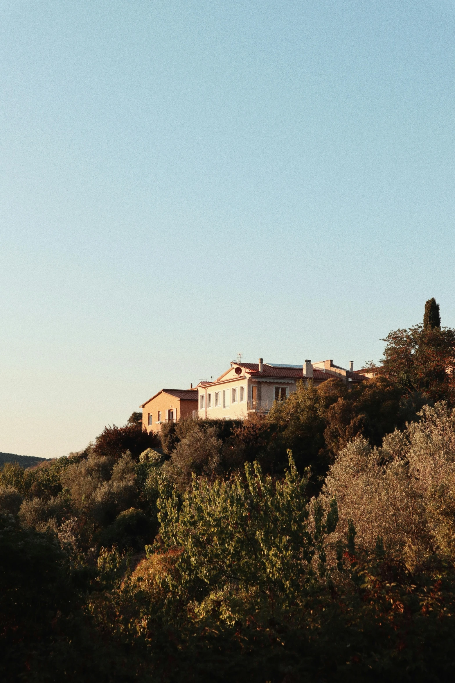 a house sits on top of a hill, looking out onto the distance