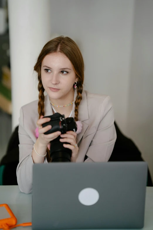 a woman holding a camera and looking at a laptop