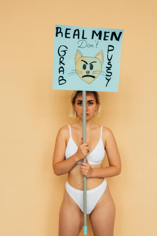 a woman in her underwear holding a sign that says real men don't play