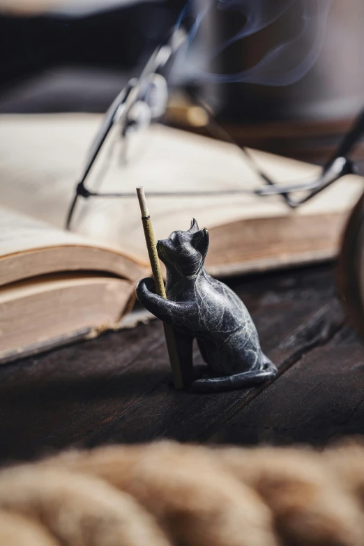 a figurine sitting on a wooden surface near an open book