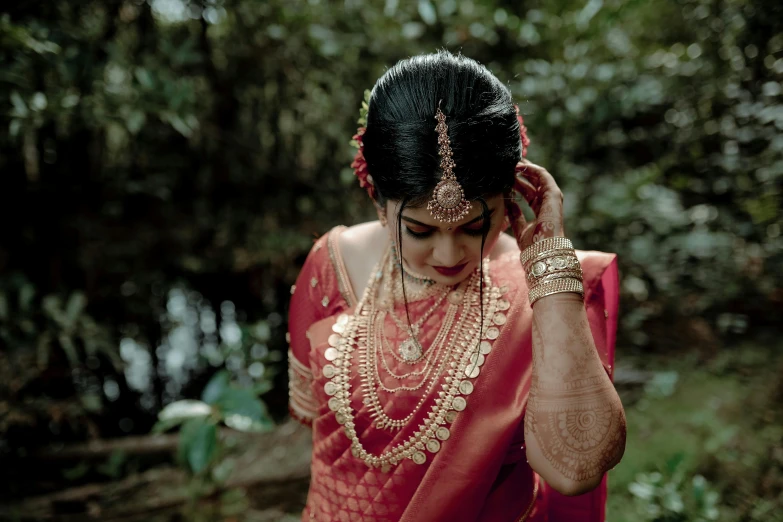 a woman is wearing a red saree and jewelry