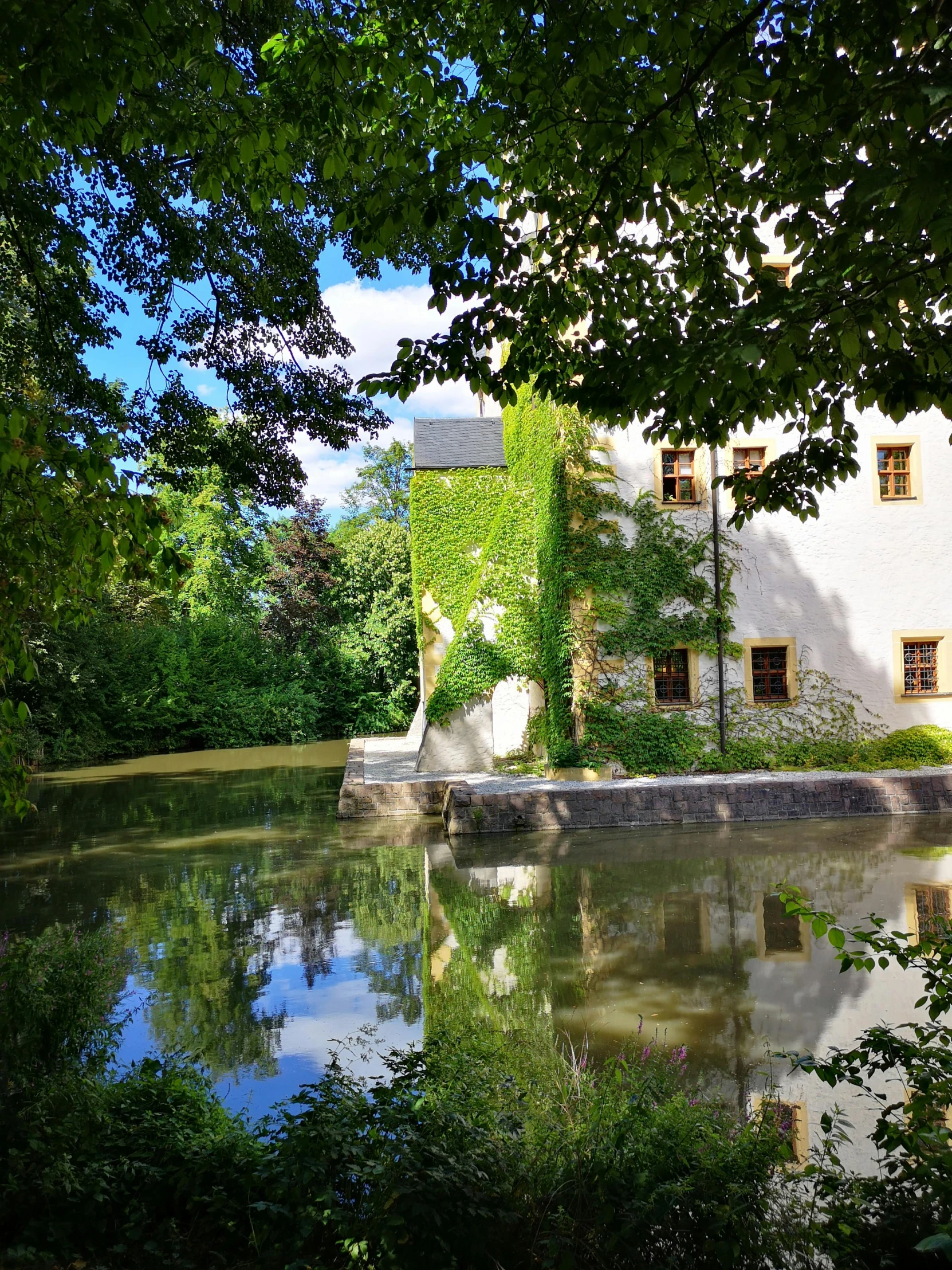 an old white house with a pond in front