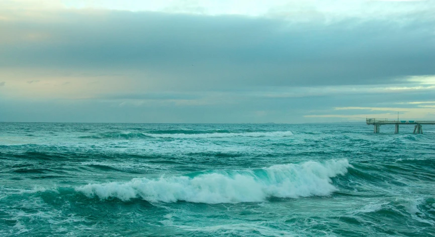 an ocean scene with a pier in the background