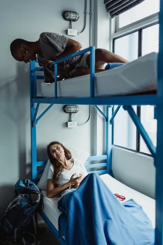 two people in bed, one reading and the other laying on the floor