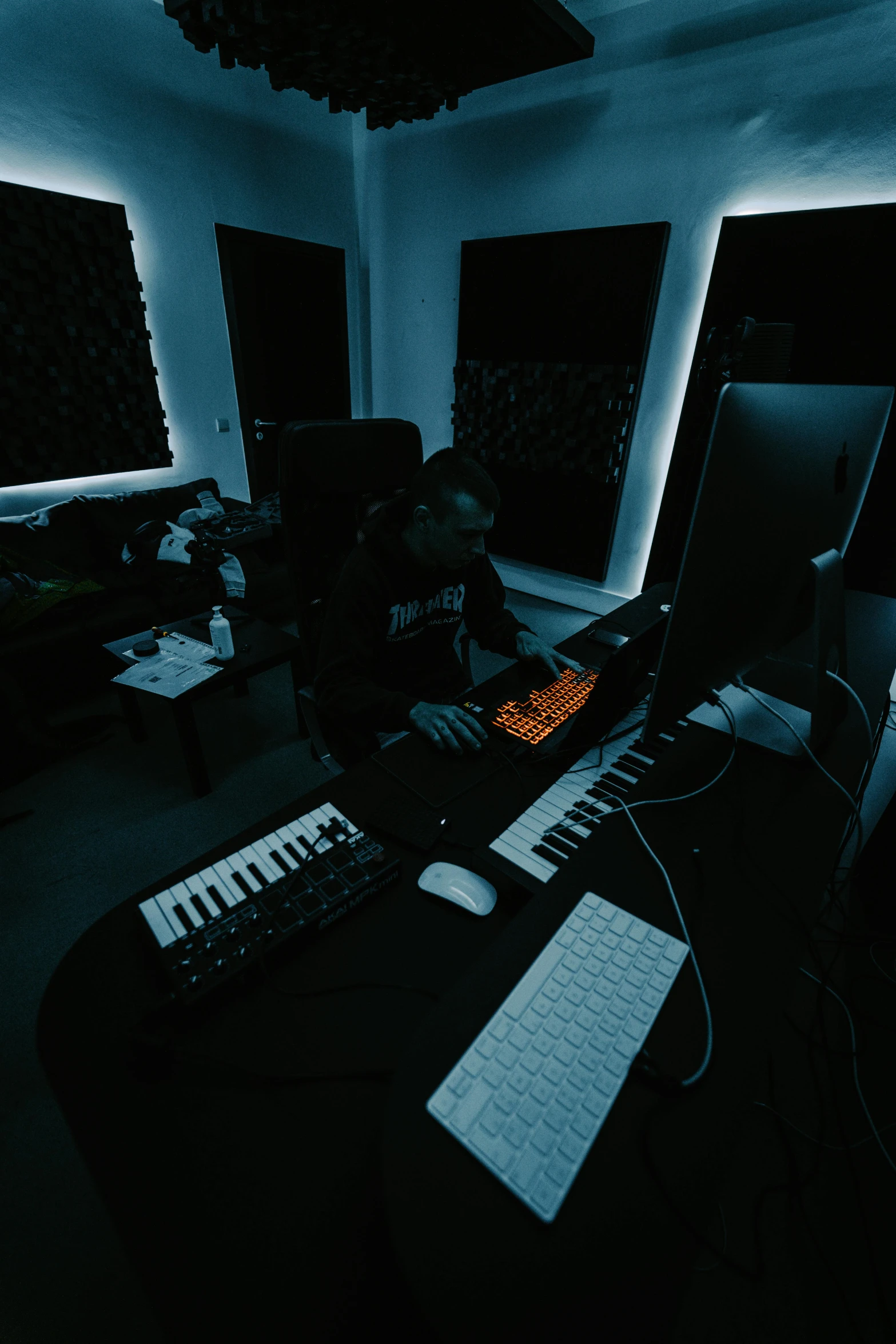 a dark room with an electronic keyboard in the center and two keyboards on the floor