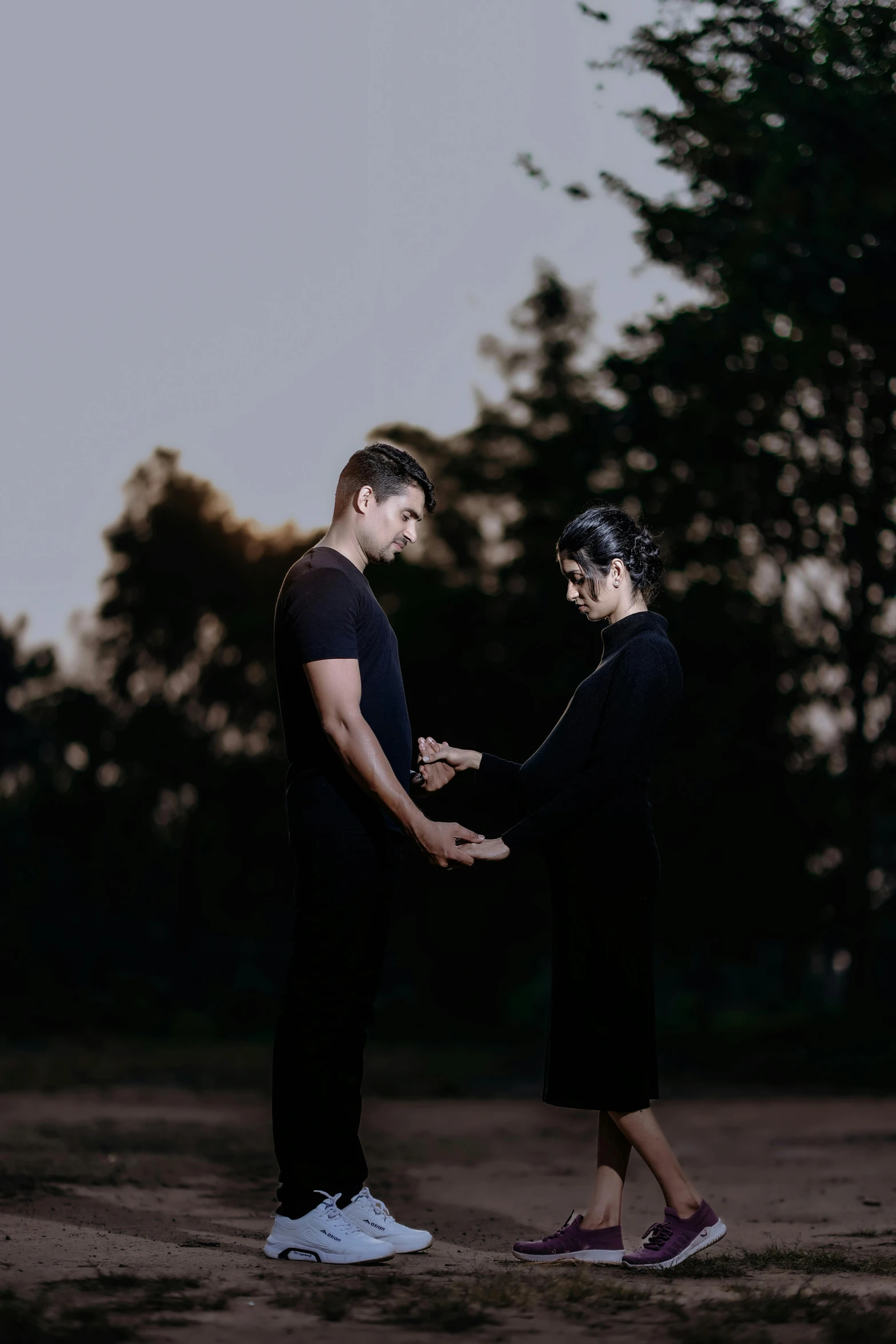 two young people holding hands and looking at each other