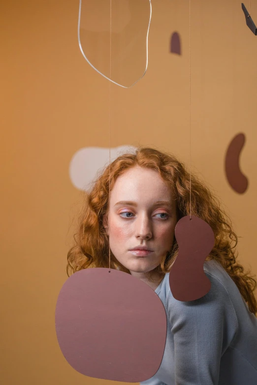 a woman with red hair standing next to a mobile