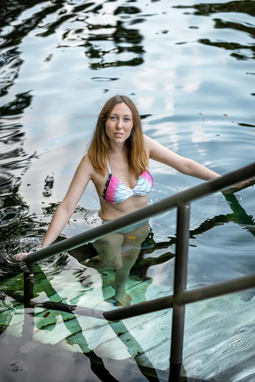 a woman in a bikini standing by a railing