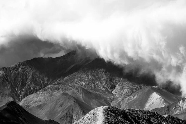 a view of mountains in black and white with some clouds in the background