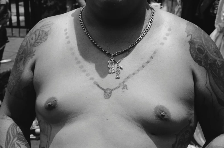 a shirtless man with a necklace is looking at the camera