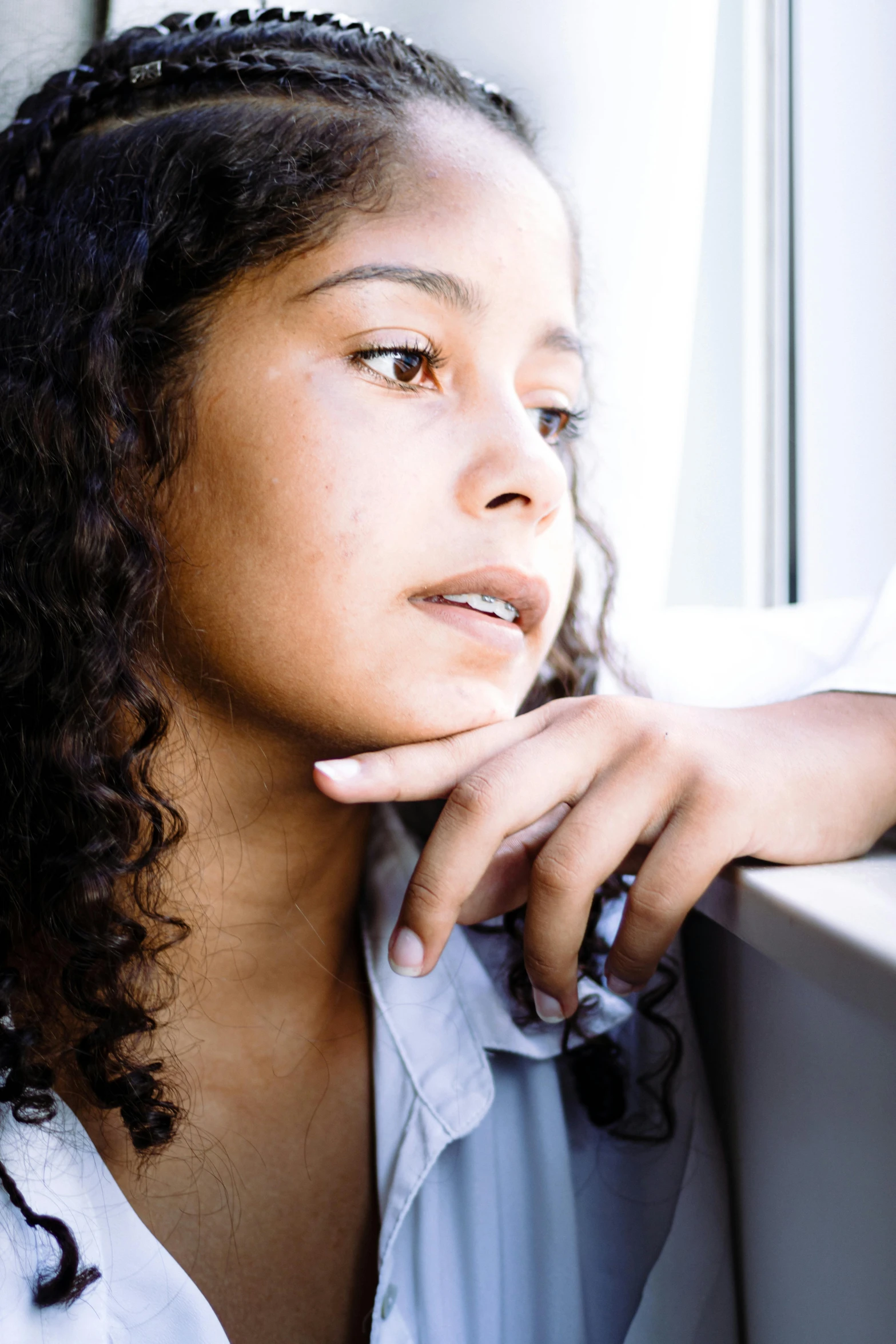 woman posing next to window in white shirt